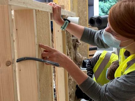 Woman putting insulation into timber frame